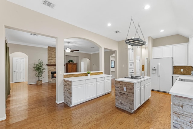 kitchen with white fridge with ice dispenser, a center island, light countertops, and white cabinetry