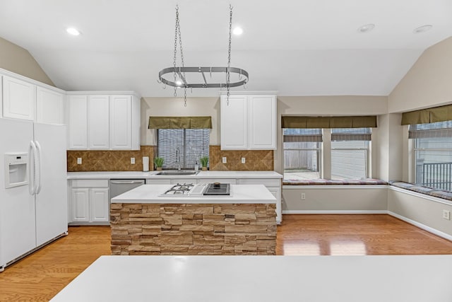 kitchen featuring white appliances, vaulted ceiling, light countertops, white cabinetry, and a sink