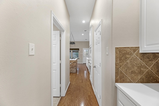 corridor with baseboards, wood finished floors, and recessed lighting