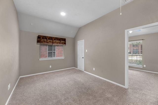 unfurnished room with carpet, attic access, vaulted ceiling, and baseboards