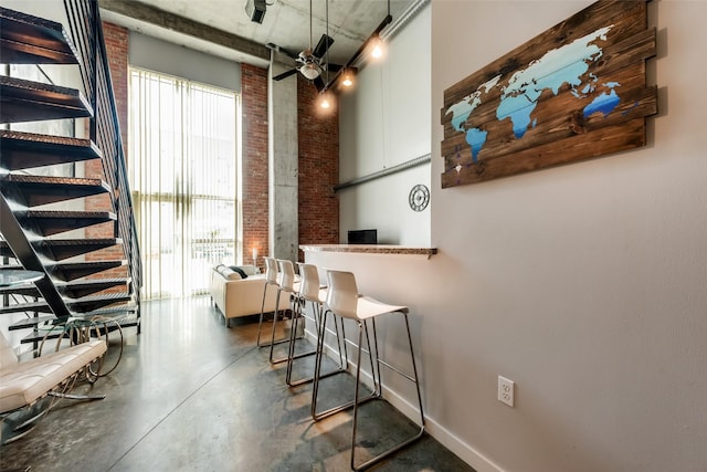 dining area with baseboards, a healthy amount of sunlight, concrete floors, and brick wall