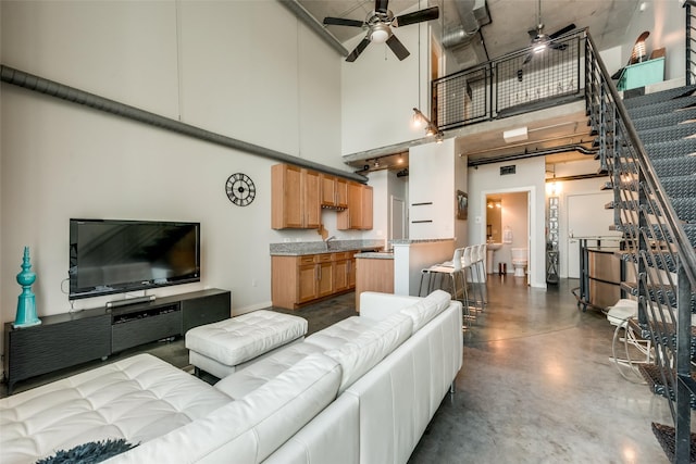 living area featuring visible vents, a towering ceiling, finished concrete flooring, stairs, and a ceiling fan