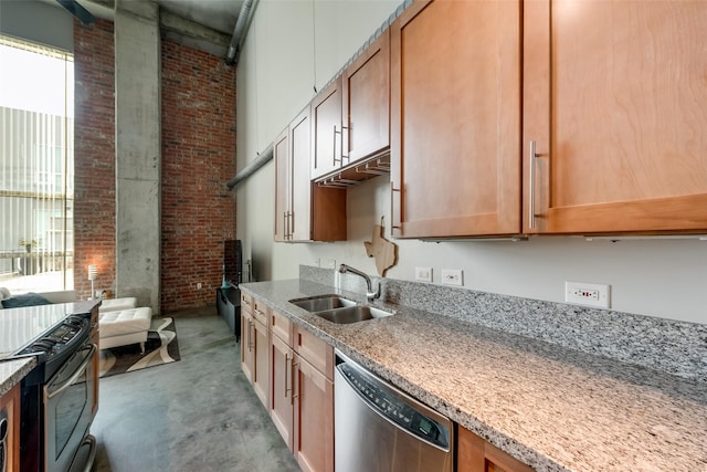 kitchen featuring light stone counters, stainless steel appliances, a towering ceiling, a sink, and brick wall