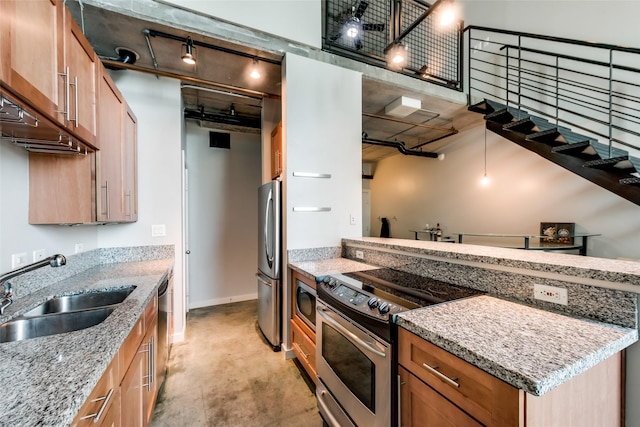 kitchen with light stone counters, stainless steel appliances, a peninsula, a sink, and rail lighting