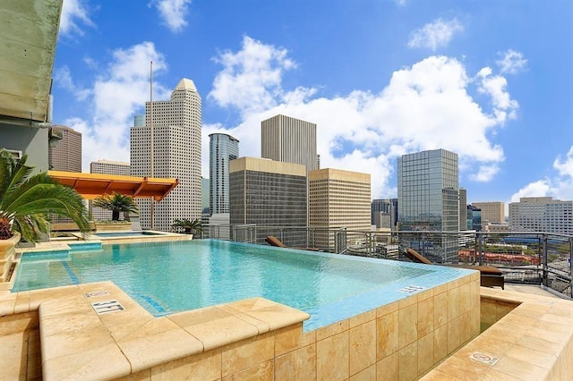 view of swimming pool with a hot tub and a view of city