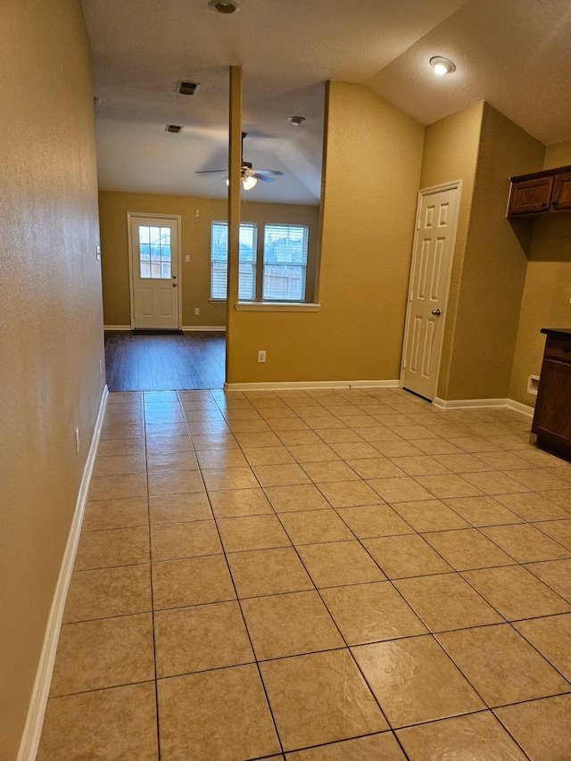 unfurnished living room with ceiling fan, vaulted ceiling, and light tile patterned floors