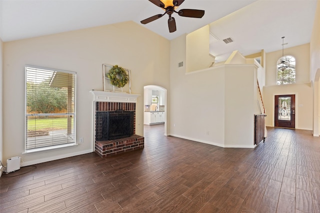 unfurnished living room featuring a brick fireplace, visible vents, high vaulted ceiling, and dark wood-style flooring