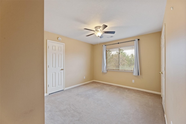 unfurnished room with a ceiling fan, visible vents, light carpet, and baseboards