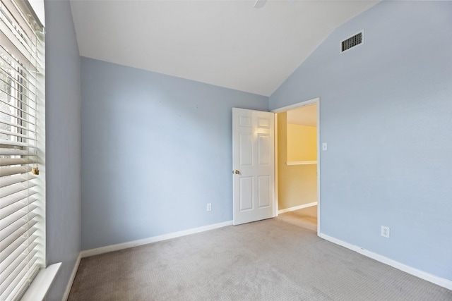 spare room with lofted ceiling, visible vents, light carpet, and baseboards