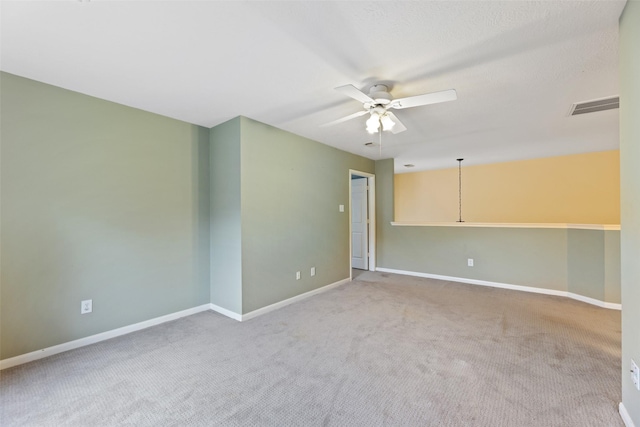 empty room with light carpet, a ceiling fan, visible vents, and baseboards