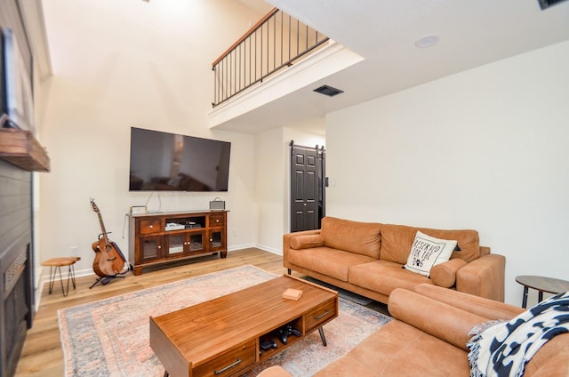 living room featuring a barn door, baseboards, and wood finished floors