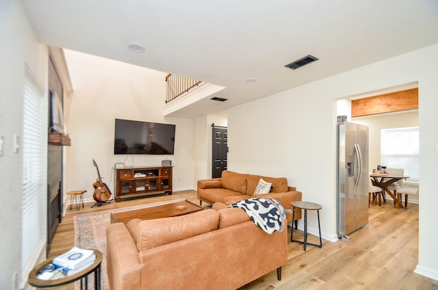 living room with light wood-style floors, baseboards, a fireplace, and visible vents