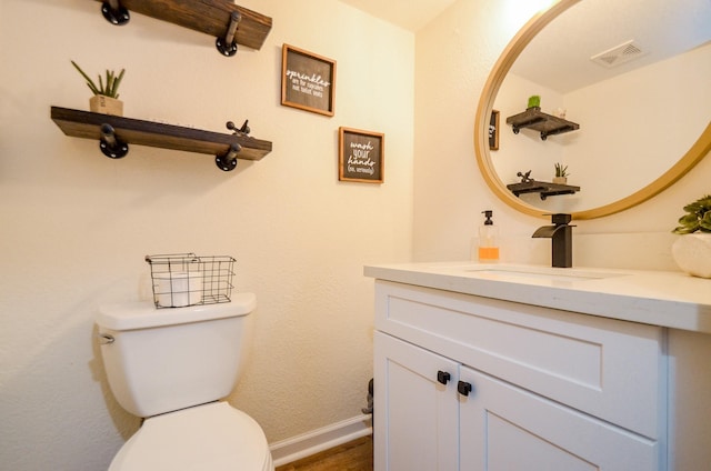 bathroom featuring baseboards, visible vents, vanity, and toilet