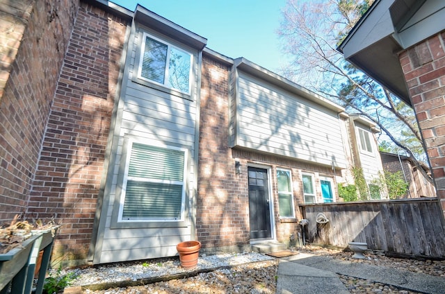 back of house featuring brick siding and fence