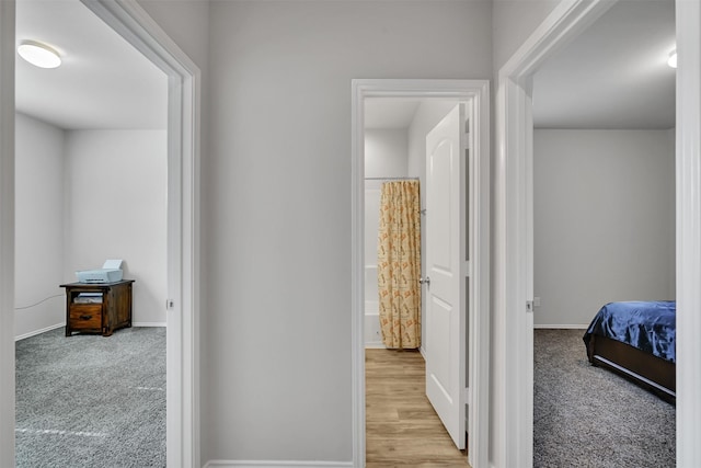 hallway featuring baseboards and light colored carpet