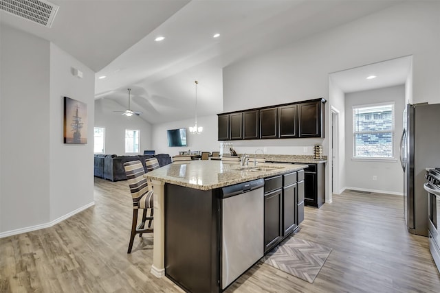 kitchen with dark brown cabinetry, a center island with sink, visible vents, appliances with stainless steel finishes, and a sink