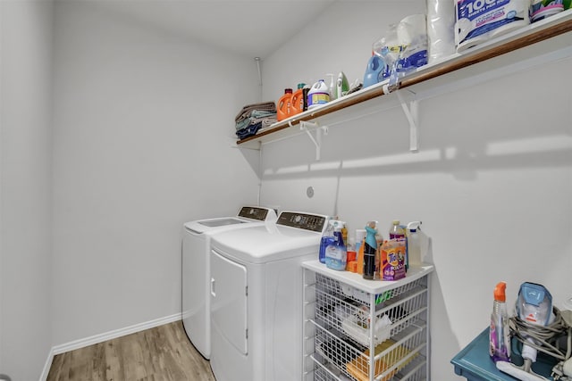 clothes washing area with laundry area, washing machine and dryer, baseboards, and wood finished floors