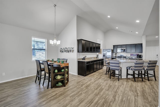 kitchen featuring light wood finished floors, a kitchen island with sink, appliances with stainless steel finishes, and pendant lighting