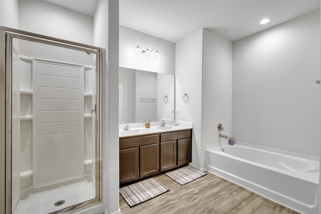 bathroom with a garden tub, a sink, a shower stall, and wood finished floors