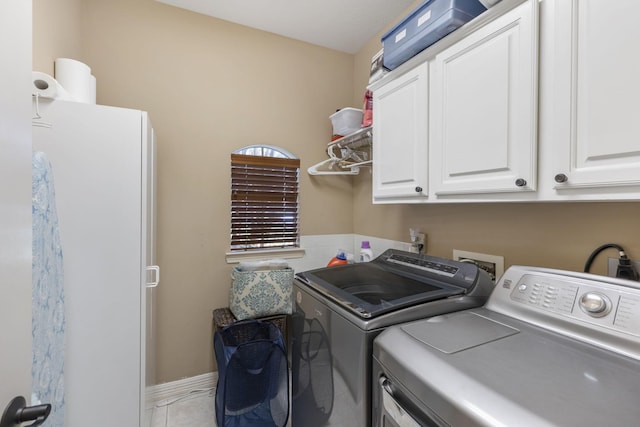 clothes washing area featuring cabinets and separate washer and dryer