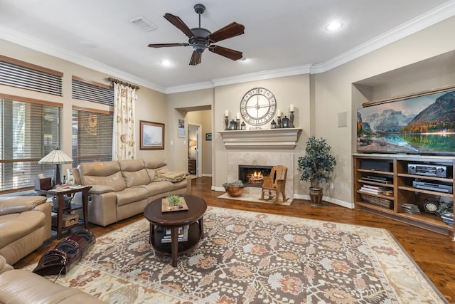 living room with crown molding, wood-type flooring, and a tile fireplace