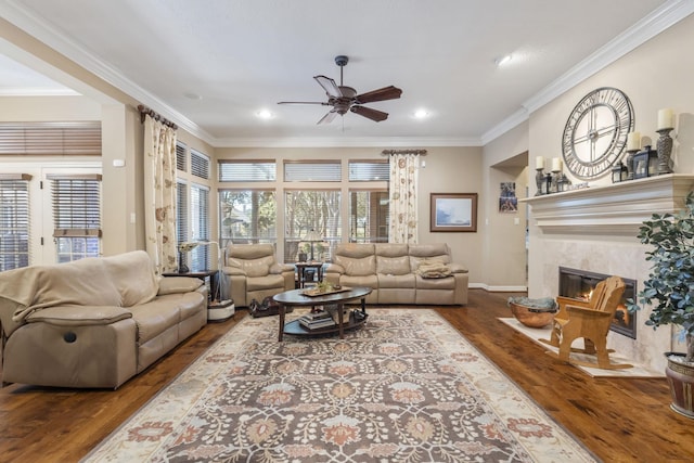 living room featuring a tiled fireplace, hardwood / wood-style floors, crown molding, and ceiling fan