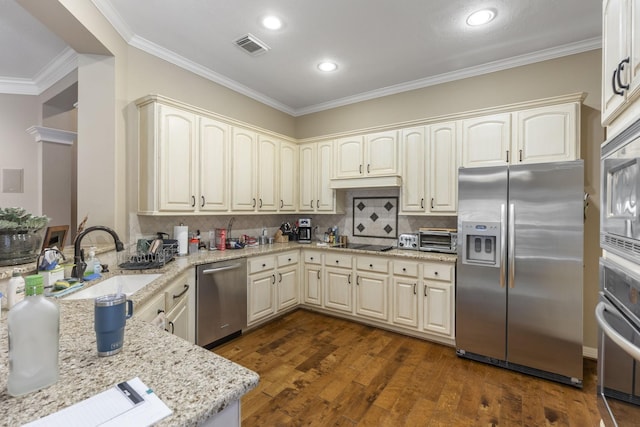 kitchen featuring sink, light stone counters, ornamental molding, appliances with stainless steel finishes, and dark hardwood / wood-style flooring