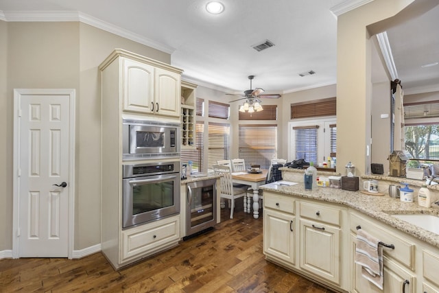 kitchen with ornamental molding, appliances with stainless steel finishes, dark hardwood / wood-style floors, and beverage cooler