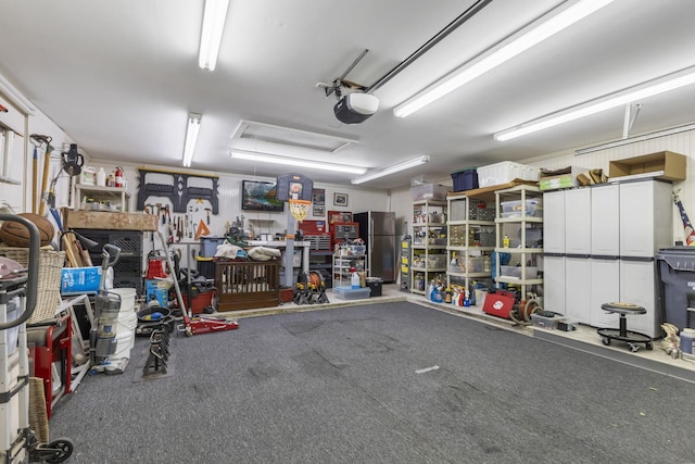 garage featuring a garage door opener, stainless steel refrigerator, and a workshop area