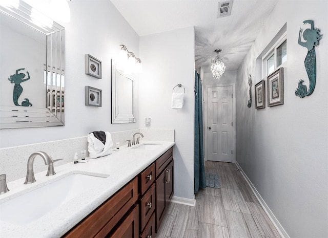 bathroom with visible vents, baseboards, a sink, and double vanity