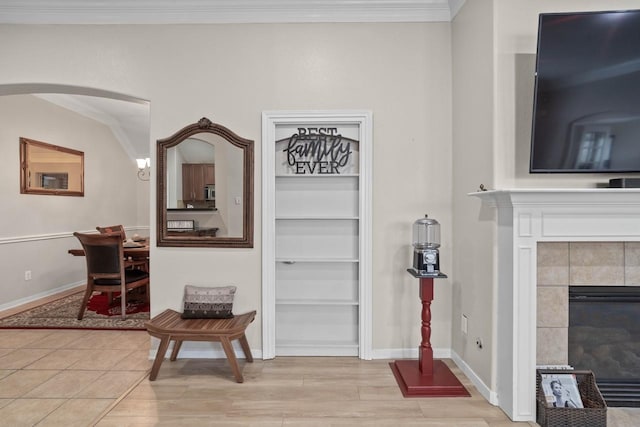 interior space with a tiled fireplace, crown molding, and light hardwood / wood-style floors