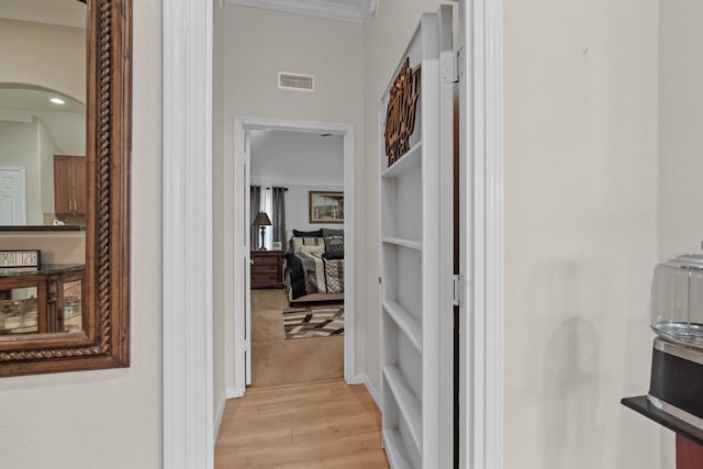 corridor featuring ornamental molding and light wood-type flooring