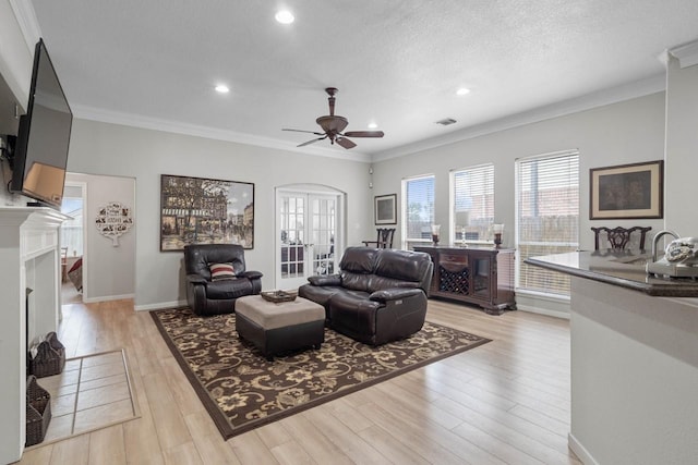 living room with light wood-type flooring, french doors, crown molding, and a textured ceiling