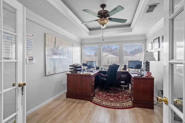 office area featuring crown molding, light hardwood / wood-style flooring, a tray ceiling, and a textured ceiling