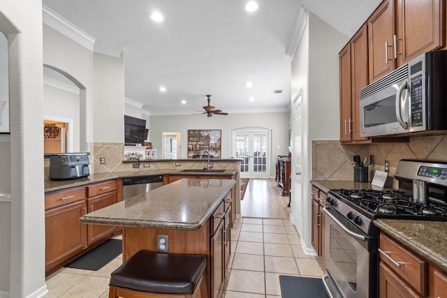 kitchen with appliances with stainless steel finishes, a breakfast bar area, a kitchen island, sink, and kitchen peninsula