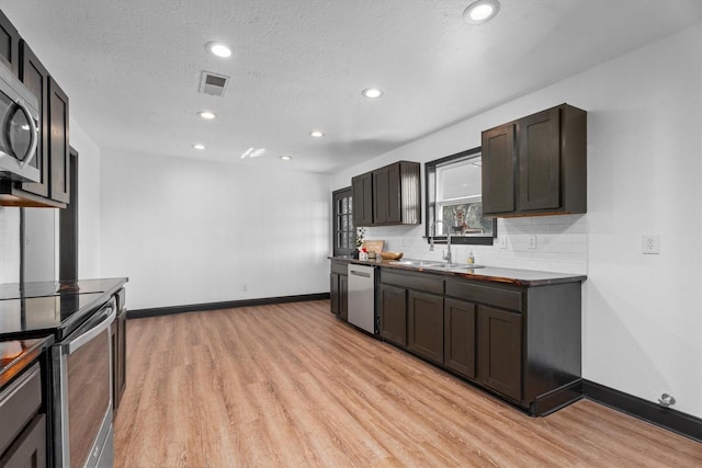 kitchen with light hardwood / wood-style flooring, sink, stainless steel appliances, dark brown cabinets, and decorative backsplash