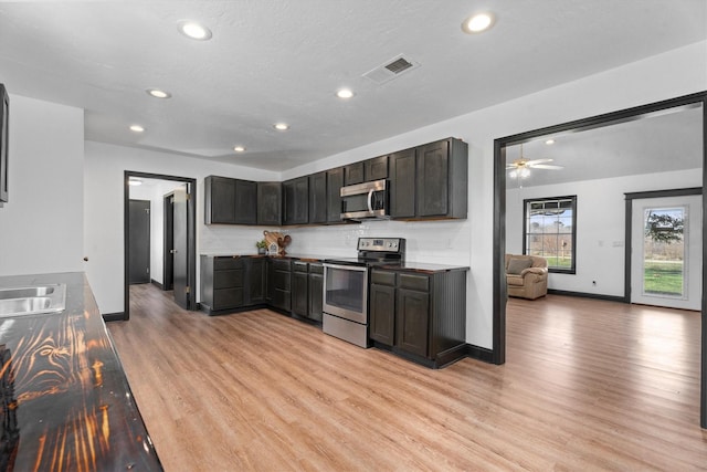 kitchen featuring light hardwood / wood-style floors, stainless steel appliances, ceiling fan, dark brown cabinetry, and tasteful backsplash