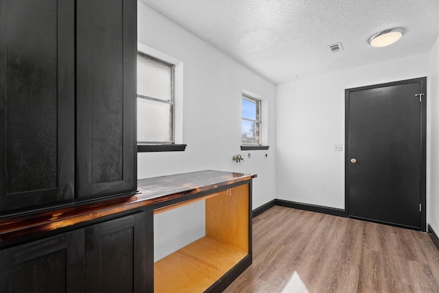 unfurnished office with light wood-type flooring and a textured ceiling