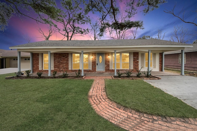 ranch-style home featuring a garage, covered porch, and a lawn