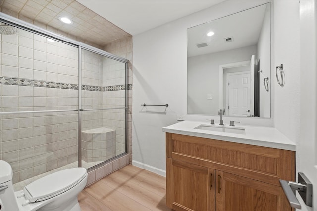 bathroom featuring vanity, a shower with shower door, wood-type flooring, and toilet