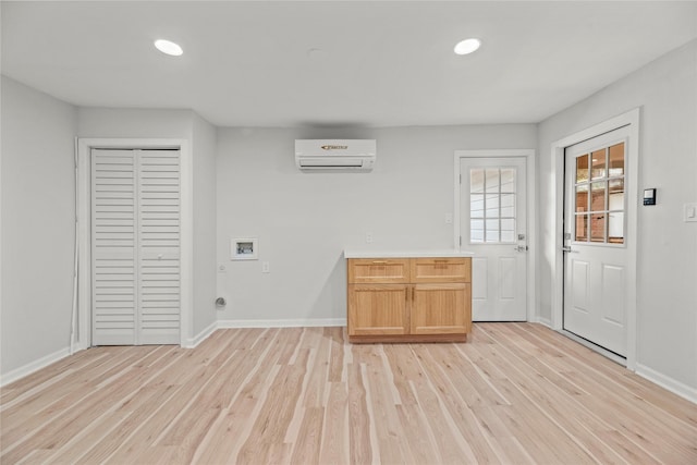 interior space featuring a wall mounted air conditioner and light hardwood / wood-style flooring