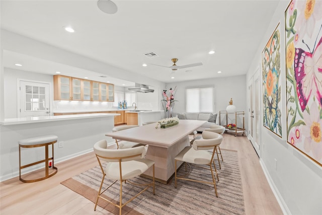 dining space featuring ceiling fan, sink, and light wood-type flooring