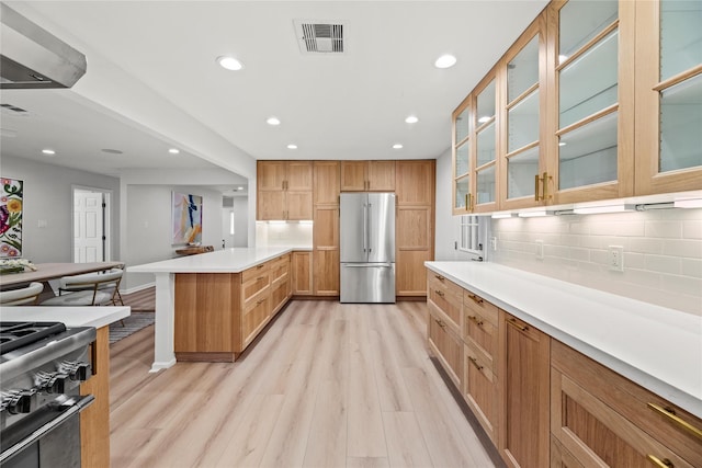 kitchen featuring black range with gas cooktop, decorative backsplash, high end refrigerator, and light wood-type flooring