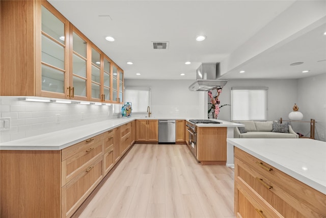 kitchen featuring sink, island exhaust hood, stainless steel dishwasher, light hardwood / wood-style floors, and kitchen peninsula