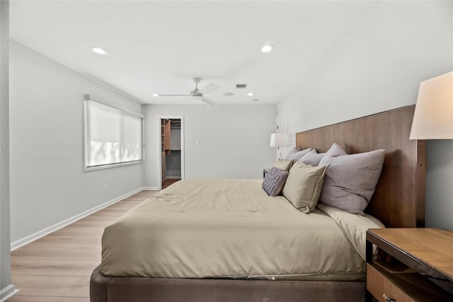 bedroom with a spacious closet, light hardwood / wood-style flooring, and ceiling fan