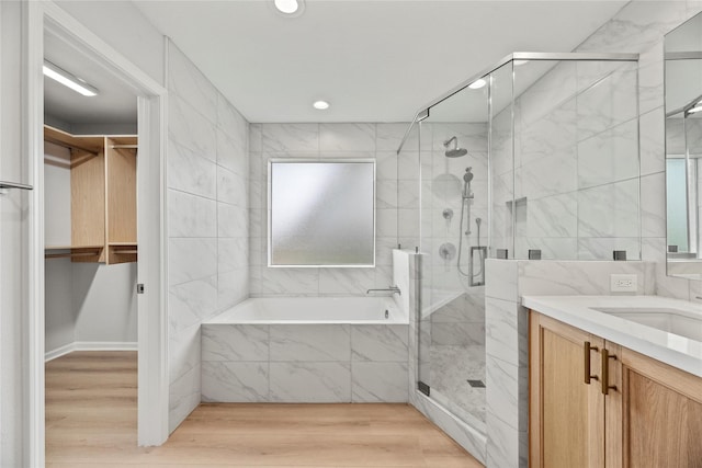 bathroom with vanity, wood-type flooring, shower with separate bathtub, and tile walls