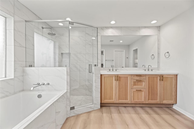 bathroom with wood-type flooring, independent shower and bath, and vanity