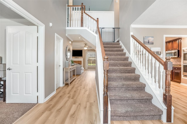 stairway featuring a high ceiling, hardwood / wood-style flooring, and crown molding