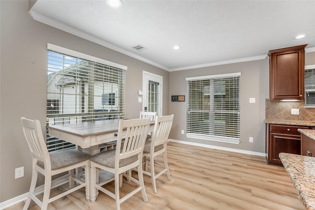 dining space with light wood-type flooring, ornamental molding, and a textured ceiling