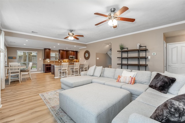 living room with crown molding, ceiling fan, and light hardwood / wood-style flooring